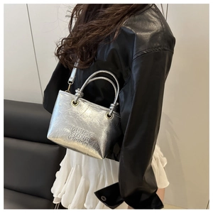 Detail of silver metallic bucket bag with ring handle worn by model in black leather jacket