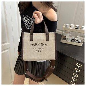 Close-up of beige canvas and brown leather stitching on a stylish tote bag with logo