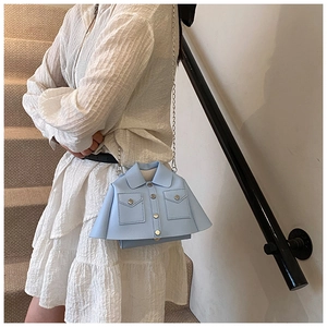 Detail of creative light blue jacket-shaped crossbody bag with silver chain and collar