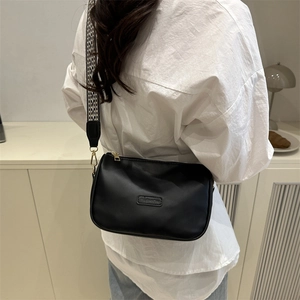 Black leather pillow crossbody bag featuring a stylish black and white checkerboard strap