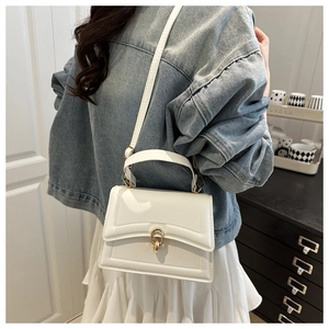 Detailed view of white leather crossbody bag with gold lock and adjustable strap
