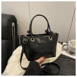 Detail of crinkled black leather texture with gold-tone hardware on casual bucket bag