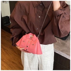 Detail of pink jacket-shaped handbag with lapel and button accents on a chain strap