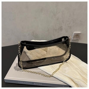 Detail view of a black translucent PVC baguette bag with fine gold chain and leather trim