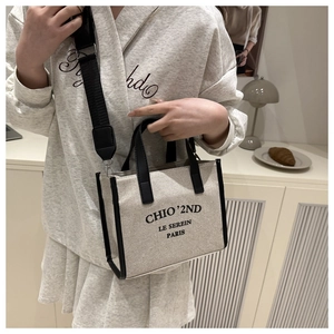 Close-up of canvas tote with black leather trim and adjustable wide shoulder strap