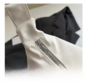 Détail d'une fermeture éclair argentée lisse sur un grand sac fourre-tout crème