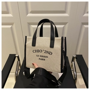 Detail of a large canvas tote bag with black leather trim and detachable shoulder strap