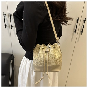 Detail of straw texture bucket bag with beige leather trim and drawstring closure