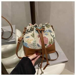 Detail of floral tapestry bucket bag with drawstring closure and leather base