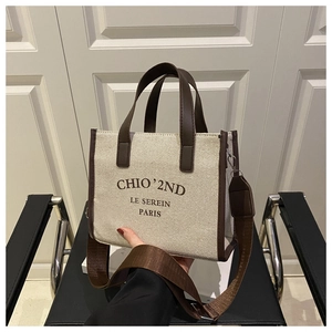 Close-up of canvas tote bag with brown leather trim and chic Paris lettering