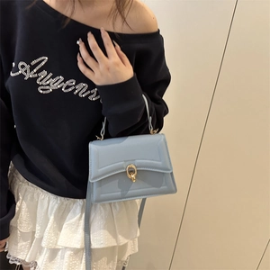 Chic light blue crossbody bag with gold ring lock and quilted texture on a model