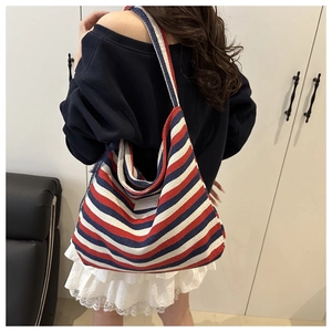 Detail of red, white, and blue striped canvas tote bag with a blank label on shoulder