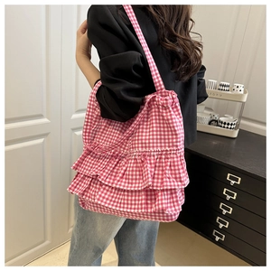 Detailed back view of pink plaid tote bag with ruffles on a female model