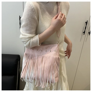 Detailed view of a pink crossbody bag featuring long fringe tassels and metal ring eyelets