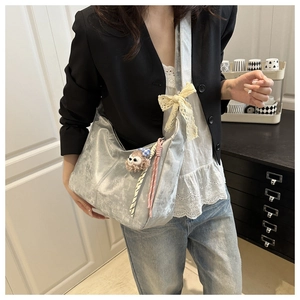 Détail du sac hobo argenté avec nœud en dentelle et pendentif en peluche mignon