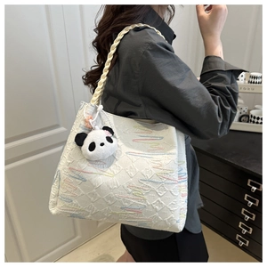 White tote bag with textured embossing and a cute panda plush charm on a woven strap