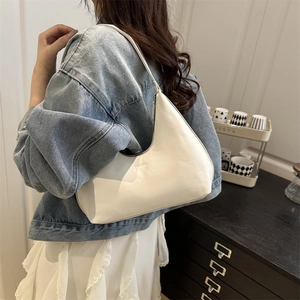 Minimalist white crescent underarm bag shown on model with denim jacket and white dress