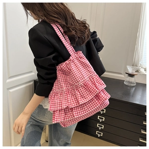 Pink and white checkered tote bag with ruffled edges shown on model in a casual setting