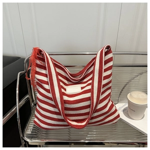 Detail of red and white striped canvas tote bag with lace ribbon on a metal rack