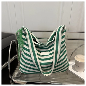 Detail showing green striped canvas tote bag with lace trim on a glass shelf