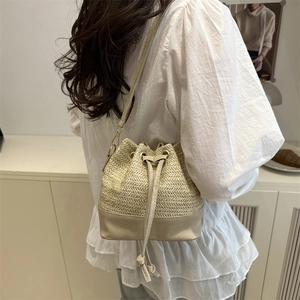 Chic straw bucket bag with contrasting leather finish and adjustable shoulder strap