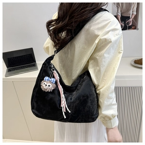 Détail du sac hobo en velours noir avec breloque nœud bleu et sangle à nœud tissé