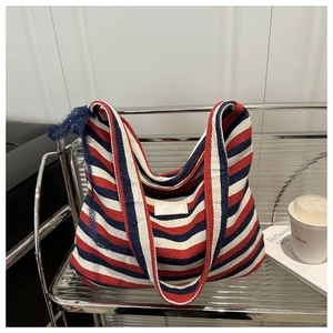 Detail of red and navy striped canvas tote bag with woven texture on a modern shelf