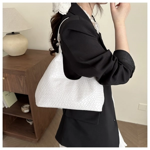 Detailed macro view of white crocodile pattern texture on a stylish crescent hobo bag