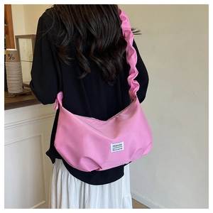 Pink crescent shoulder bag detail showing ruched strap and minimalist brand label