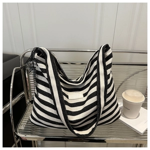 Detail of black and white striped tote bag featuring a black lace bow and canvas texture