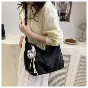Détail d'un sac bandoulière en velours noir avec peluche et ruban à carreaux bleus