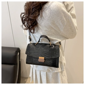 Vue arrière du sac à main noir motif crocodile avec fermoir doré porté par un modèle