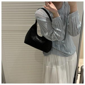 Detail of black woven crescent hobo bag shown on shoulder for commute style