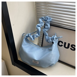 Detail of light blue nylon dumpling bag with trendy scrunchie shoulder strap and fashion label