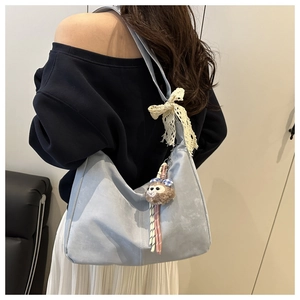 Détail d'un sac hobo bleu en daim avec bandoulière en dentelle et pendentif peluche