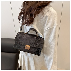 Détail du sac bandoulière noir à motif crocodile avec fermoir doré et poignée