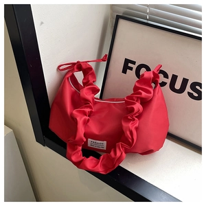 Detail of red nylon dumpling bag with pleated shoulder strap and Fashion label tag