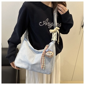 Détail du sac hobo bleu clair avec nœud en dentelle et charmant pendentif ours en peluche