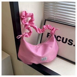 Detailed view of pink nylon dumpling bag with pleated strap and fashion label on front