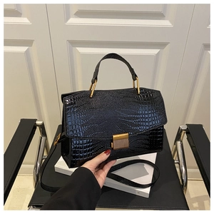 Gros plan sur la texture crocodile noir et le fermoir rétro en métal du sac à main