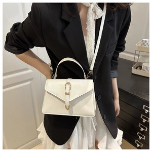 Détail d'un sac bandoulière blanc enveloppe avec un fermoir doré élégant et minimaliste