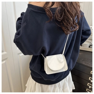 Back view of a model wearing a mini white crossbody bag with lychee texture leather finish