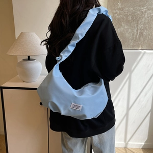 Light blue minimalist dumpling bag in soft padded nylon for stylish daily commute