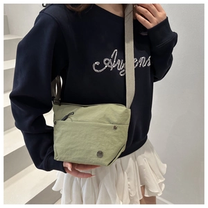Detail view of the sage green nylon crossbody bag with wide strap and metallic logo