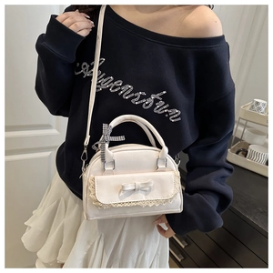 Close-up of white handbag featuring lace edges, bows and a plaid ribbon on handle