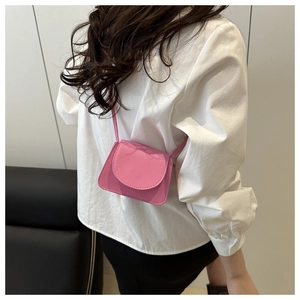 Detail view of a pink mini crossbody bag with litchi grain texture worn by a model