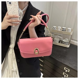 Detail of bright pink leather handbag featuring a golden horseshoe metallic buckle clasp