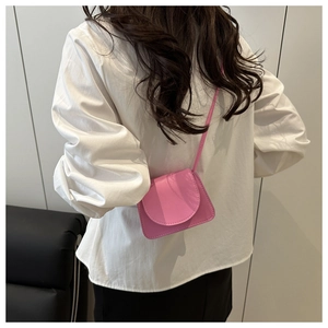 Detail of pink mini crossbody bag with litchi texture on a female model with a slim strap
