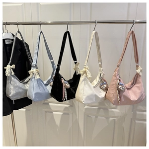 Détail de sacs hobo décontractés en cinq couleurs avec nœuds en dentelle et breloques