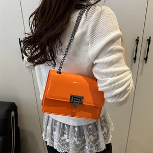 Fashionable bright orange patent leather square crossbody bag with metallic chain strap